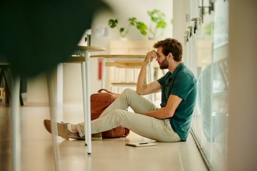 Sad student sitting on the floor on the corridor of a university.