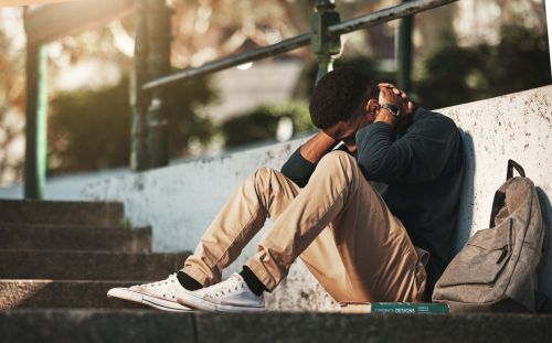 Sad student sitting with his hands in his face.