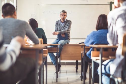 Serious professor sitting on the table